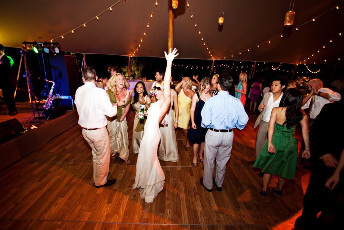 Wedding guests dancing under warm tent lights
